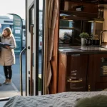 Camping car haut de gamme : cuisine et literie de luxe ouvertes sur parking