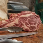 Viande persillée : gros plan côte crue persillée devant boucherie