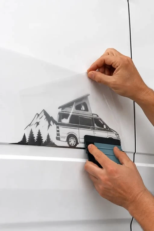 Pose de stickers van aménagé sur une carrosserie propre avec film de transfert et raclette