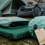 Matelas rando autogonflant R-Value près d’un refuge, herbe humide, nuit froide